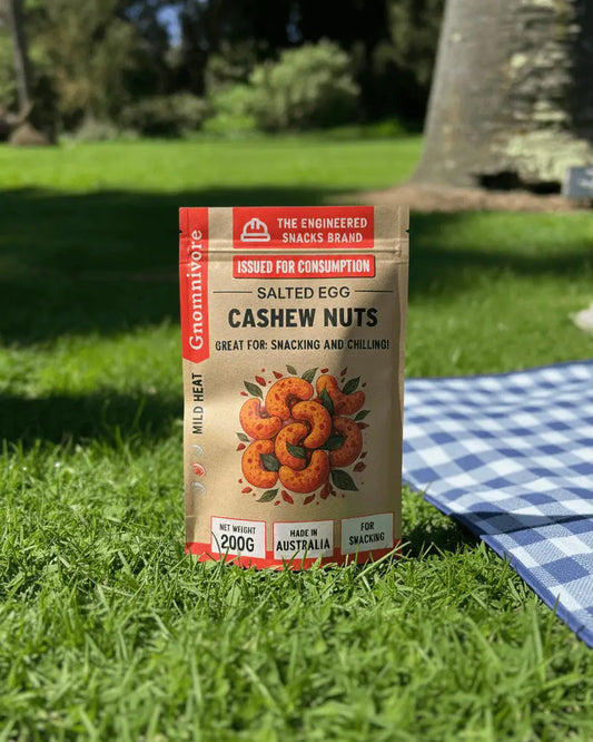 Gnomnivore Engineered spicy snacks, package of salted egg cashew on picnic secenary.