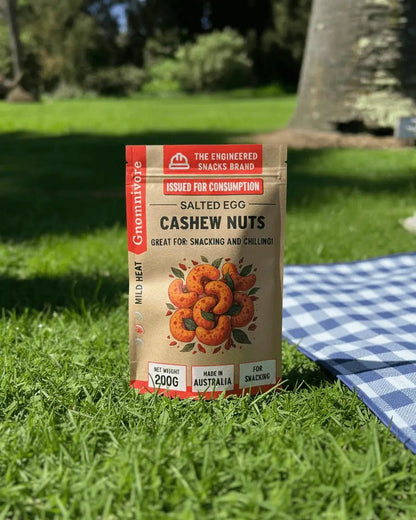 Spicy Salted Egg Cashew Nuts package in 200g, on a picnic matt in a garden